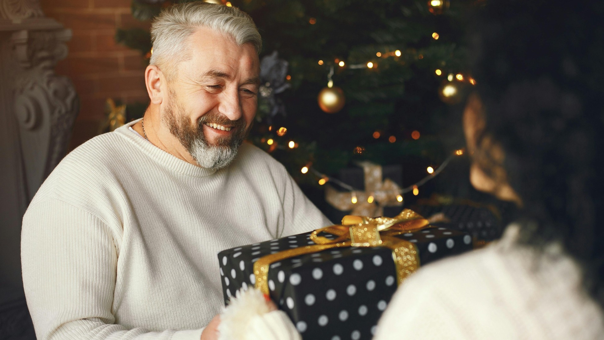 Děda se směje při rozbalování vánočního dárku s rodinou